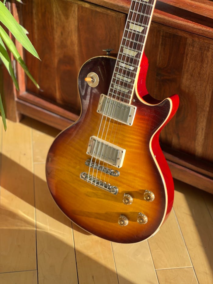 Sunburst electric guitar on a warm-toned wooden floor with natural lighting.